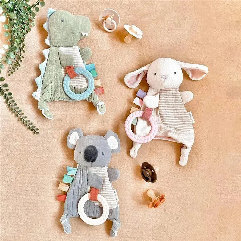Bitzy Crinkle Sensory Crinkle Toy with Teether in a koala design, surrounded by other animal toys and pacifiers.