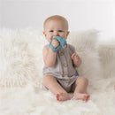 Baby sitting on a fluffy surface, holding a blue silicone elephant-shaped teether with an easy-to-hold grip.
