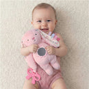 Smiling baby holding a soft pink bunny toy featuring a mirror and colorful tags, designed for sensory development.