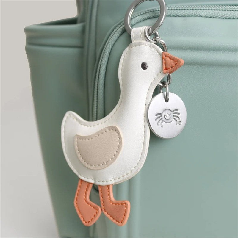 Backpack diaper bag keychain features a plush duck design with a silver tag, attached to a light green bag.