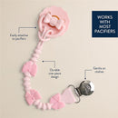 Pink silicone pacifier clip with bow designs, featuring a durable one-piece construction and a metal clip for attachment.