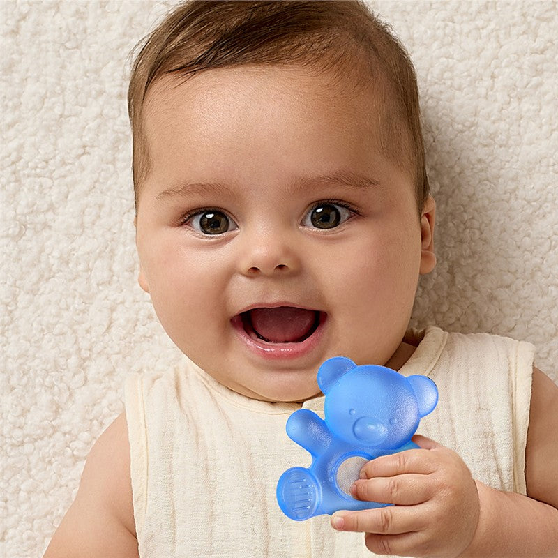 Smiling baby holding a blue bear-shaped teether against a light textured background.