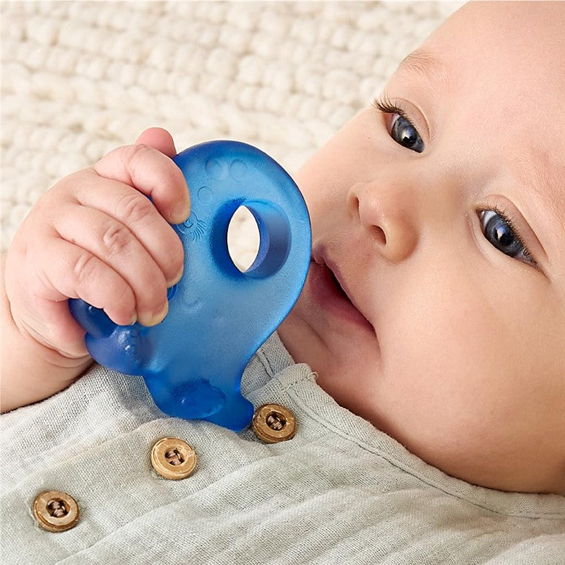 Baby holding a blue octopus-shaped teether while sitting on a textured surface, wearing a light shirt with buttons.