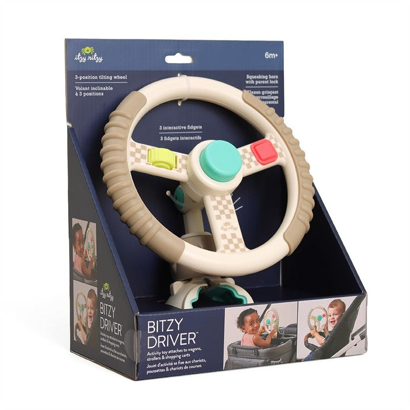 Taupe Itzy Ritzy Driver Travel Steering Wheel with interactive fidgets, designed for infants 6 months and older, packaged in a decorative box.