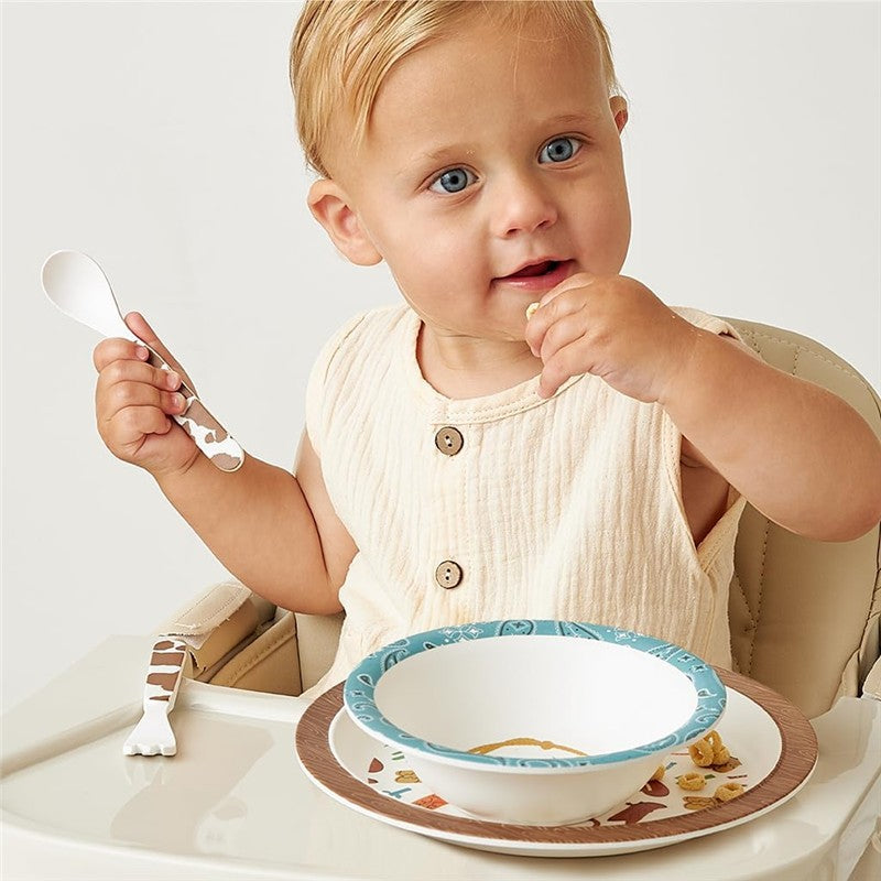 Toddler enjoying a meal in a high chair, using a decorated spoon, with the Itzy Ritzy Bistro dining set displayed.