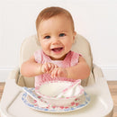 Smiling baby in a high chair, with a pink knitted top, surrounded by a floral Ribbons & Roses dining set.