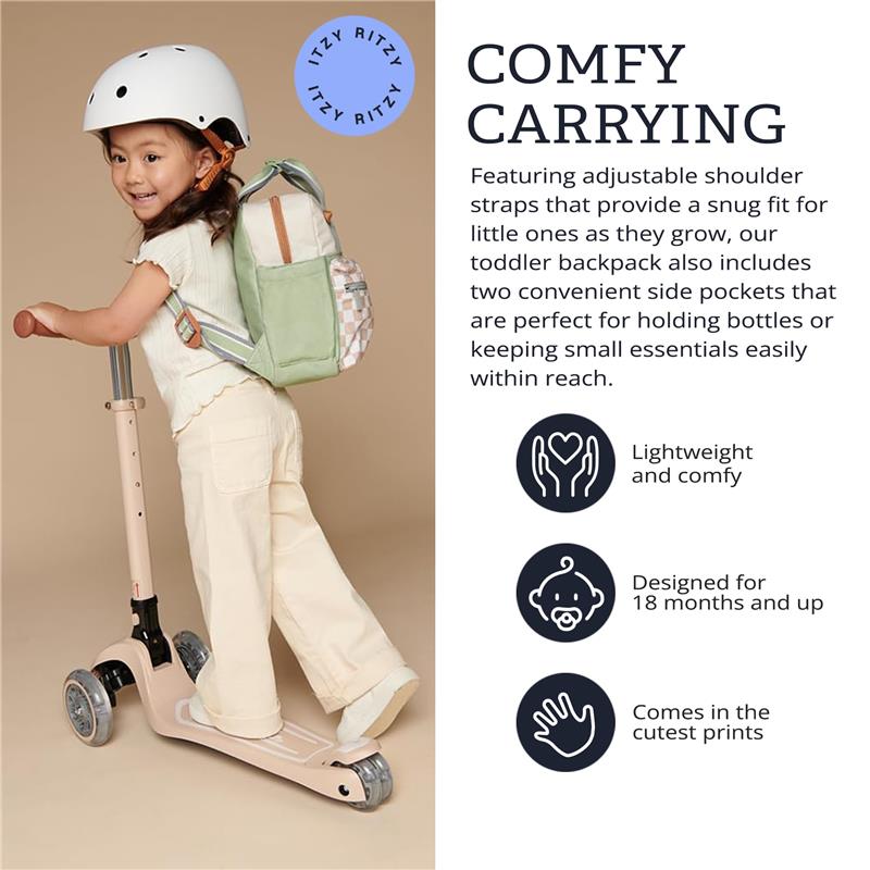 Toddler riding a scooter wearing a helmet, carrying an Itzy Ritzy Itzy Bitzy Bag™ backpack in a green and cream color scheme.