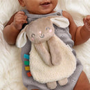 Soft plush bunny toy from the Itzy Ritzy Learn & Snuggle Gift Set, cuddled by a smiling baby in a gray onesie.