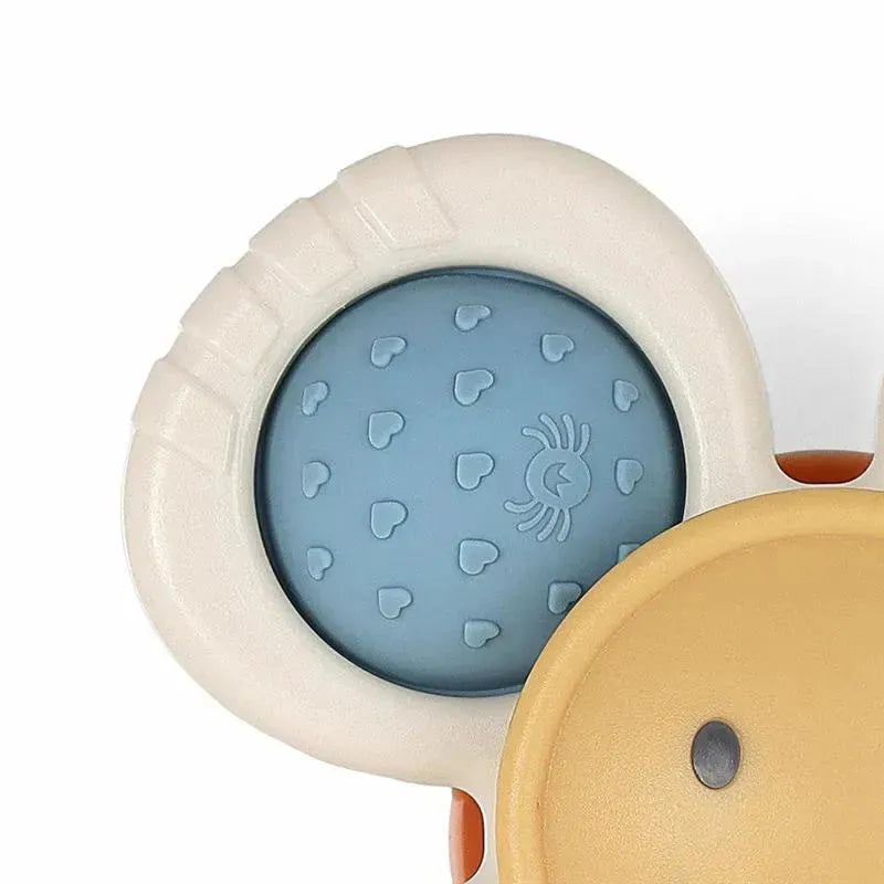 Itzy Ritzy Itzy Pop & Whirl toy with a textured blue center featuring hearts and a yellow exterior shape.