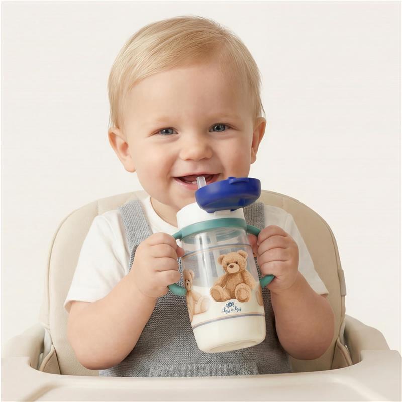 Toddler sitting in a high chair, smiling while holding the Itzy Ritzy Itzy Sips Straw Cup with a blue lid and bear design.