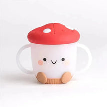 Itzy Ritzy Itzy Snack Cup™ in mushroom design, featuring a smiling face, red cap, and handles for easy gripping.