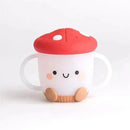 Itzy Ritzy Itzy Snack Cup™ in mushroom design, featuring a smiling face, red cap, and handles for easy gripping.