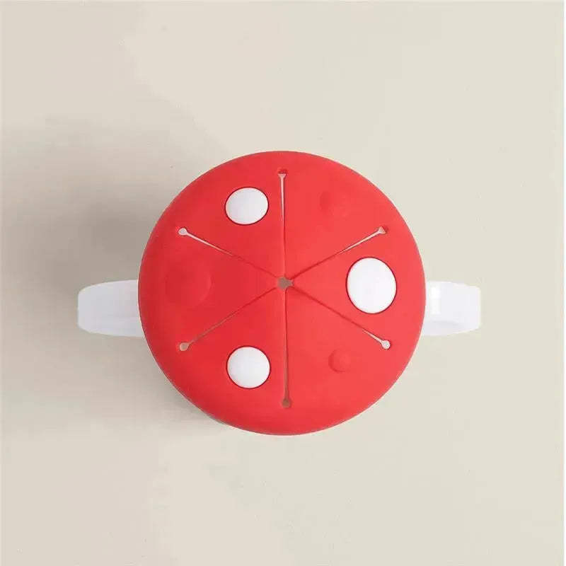 Red Itzy Ritzy Snack Cup™ in mushroom design, featuring white dots and slits, highlighting its snack compartment.