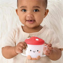 Toddler smiling while holding the Itzy Ritzy Itzy Snack Cup™, designed like a mushroom with a red cap and smiling face.