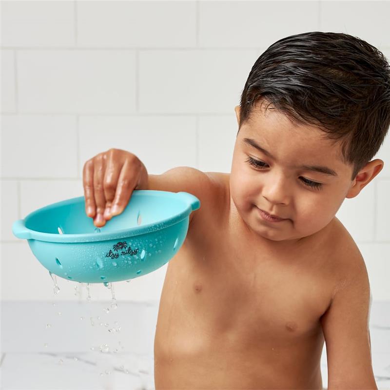 A young child bathes while holding a blue Itzy Ritzy toy bowl, splashing water as it drips from the edges.
