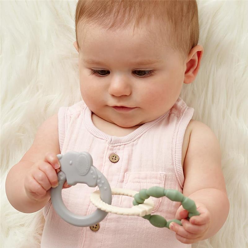 Baby holding a grey elephant-shaped teething ring and a green textured ring from the Itzy Ritzy Linkable Teething Ring Set.