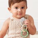A toddler holds the Itzy Ritzy Linkable Teething Ring Set featuring an elephant-shaped ring and two additional textured rings.