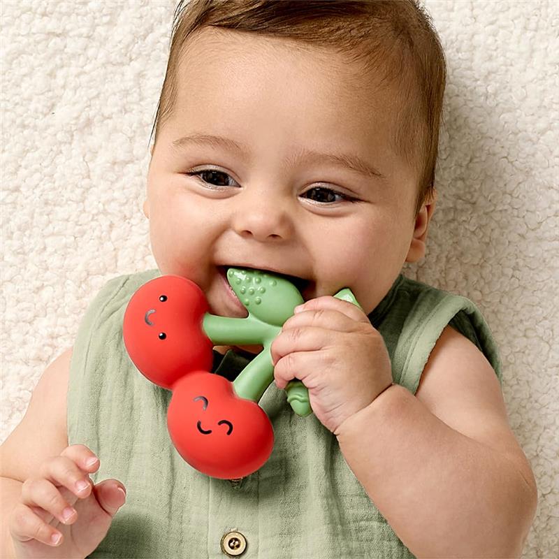 Baby happily chewing on a red and green Itzy Ritzy natural rubber teether shaped like cherries.