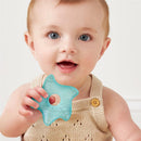 Baby holding a blue star-shaped Itzy Ritzy Seaside Cooling Teether, smiling with mouth open, wearing a beige knitted outfit.