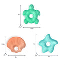 Three sea-themed cooling teethers: a turtle, a shell, and a starfish, each with unique textures and colors.