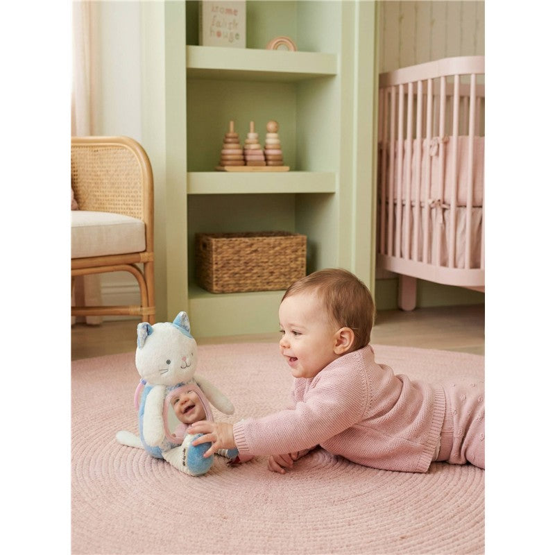 Baby playing on a pink rug with Itzy Ritzy Sensory Tummy Time Mirror featuring Kinsley the Kitty, smiling and reaching out.
