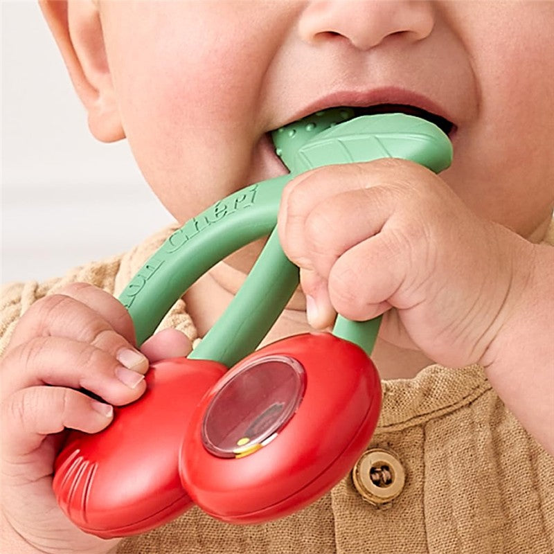 Silicone teether shaped like cherries with a rattle feature, being held by a baby.
