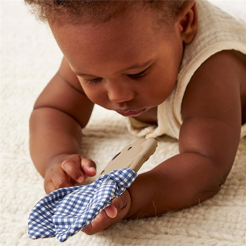 Baby exploring an Itzy Ritzy Silicone Teether shaped like a bear, featuring a blue checkered crinkle tie.