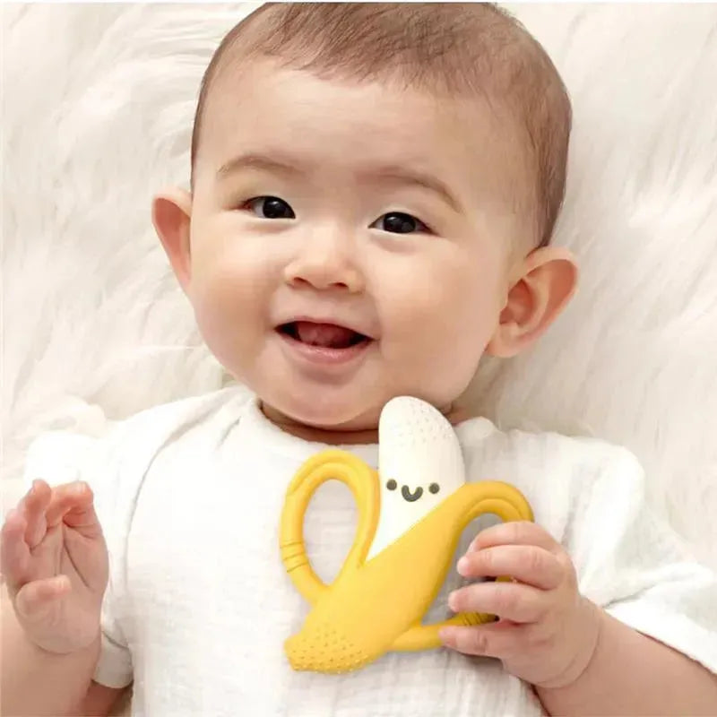 Smiling baby holding a yellow silicone teether shaped like a banana with easy-grab handles.