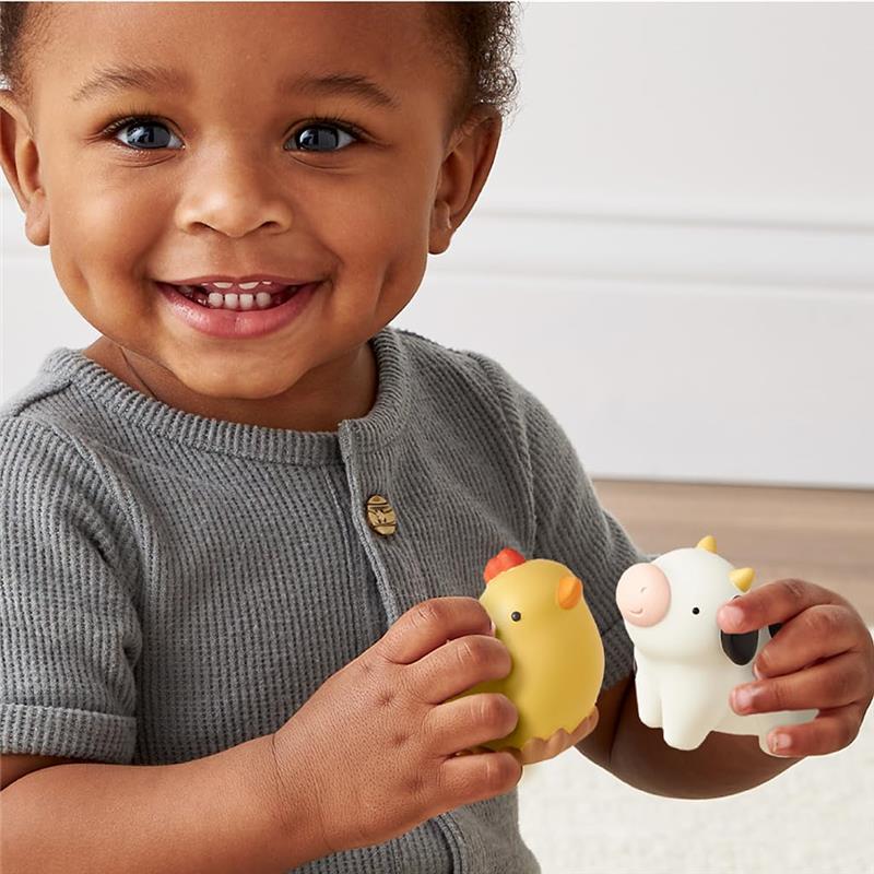 Smiling child holds a yellow chicken and a white cow toy from the Itzy Ritzy Spill and Fill Activity Toy set.