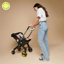 Itzy Ritzy Spiral™ Car Seat Activity Toy attached to a stroller with a smiling baby inside, while a woman pushes it.