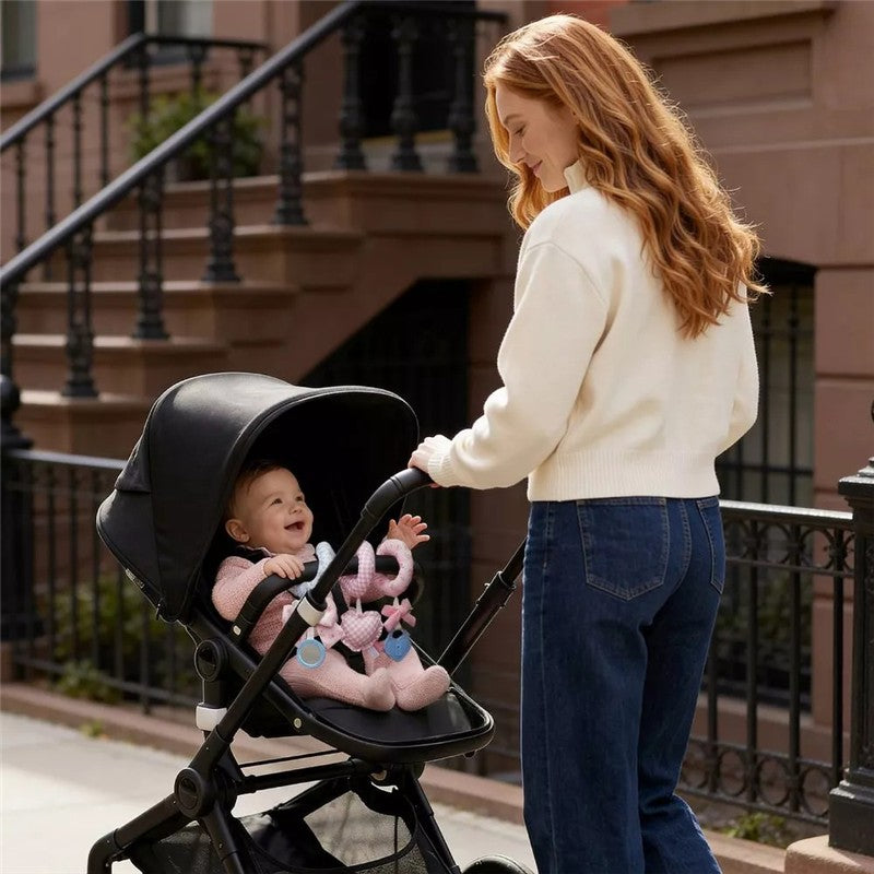 Mother with long red hair interacts with a smiling baby in a stroller, featuring the Itzy Ritzy Spiral™ Car Seat Activity Toy.