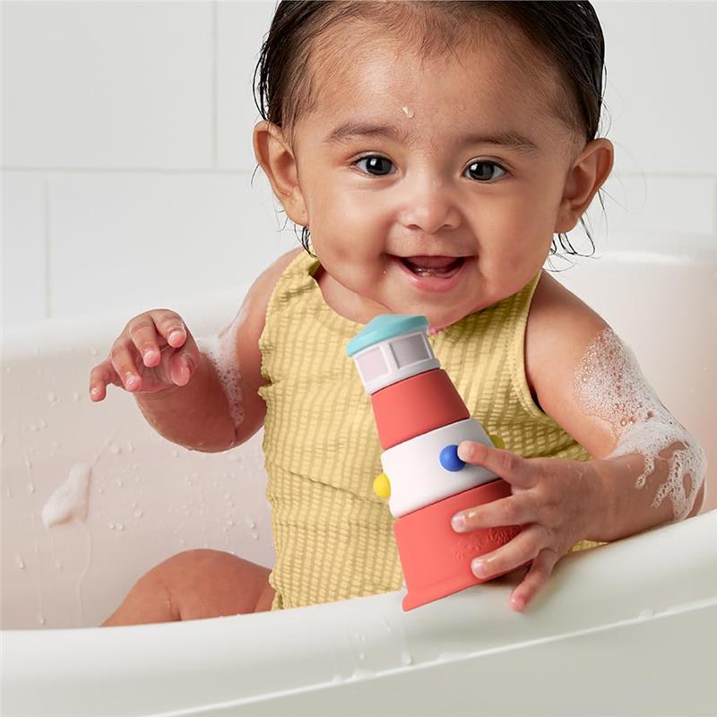 Happy baby in a bathtub holding a nautical lighthouse bath toy, surrounded by bubbles.