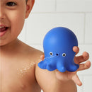 Blue octopus bath toy, designed to squirt water, held by a smiling child in a bathroom setting.