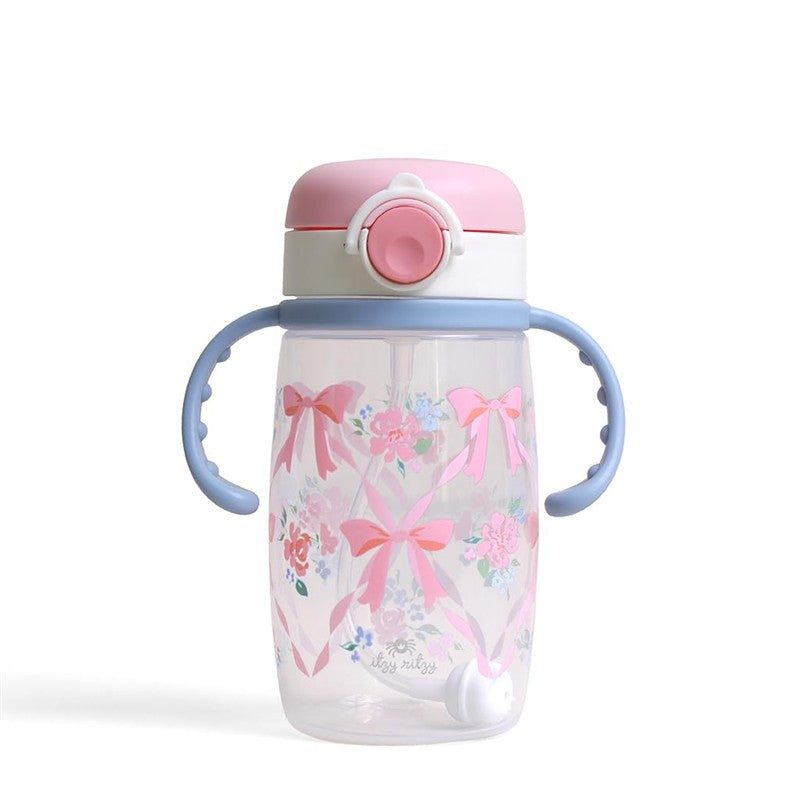 Sippy cup with a pink lid and blue handles, featuring a floral design with ribbons and bows.