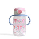 Sippy cup with a pink lid and blue handles, featuring a floral design with ribbons and bows.