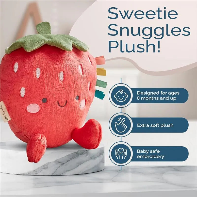 Sweetie Snuggles Plush is a soft strawberry-shaped toy with blushing cheeks and colorful tags, designed for babies.