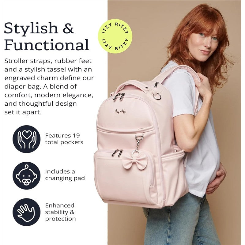 Pink Itzy Ritzy Boss Plus™ Backpack Diaper Bag shown worn on a model, featuring a bow, 19 pockets, and a changing pad.