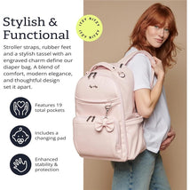 Pink Itzy Ritzy Boss Plus™ Backpack Diaper Bag shown worn on a model, featuring a bow, 19 pockets, and a changing pad.