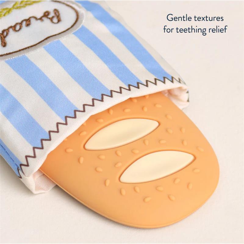 Teething relief silicone teether shaped like a baguette, partially covered by a blue and white striped fabric.