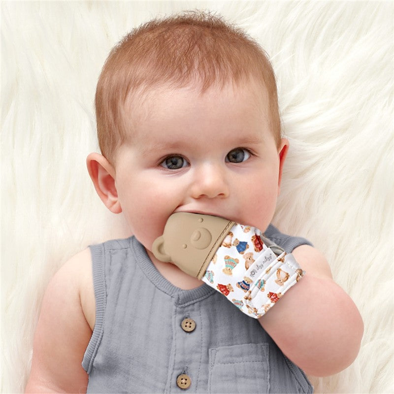 Baby wearing the Itzy Ritzy Teething Mitt - Classic Bears, nibbling on the mitt, surrounded by soft white fur.