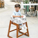 A young child sits in a wooden high chair covered with a Disney Baby disposable cover featuring cartoon characters.