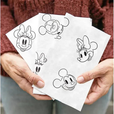 Disposable changing pads featuring Disney Baby designs with Mickey and Minnie Mouse illustrations, held in hands.