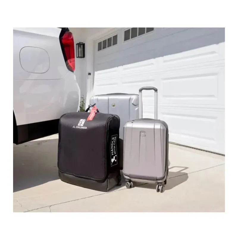 Compact padded travel bag for strollers by J.L. Childress, alongside two wheeled suitcases, near a car.