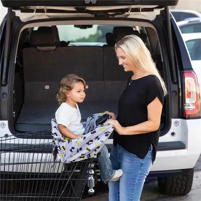 Shopping cart cover featuring a Batman design, with a child seated, as a woman prepares to shop.