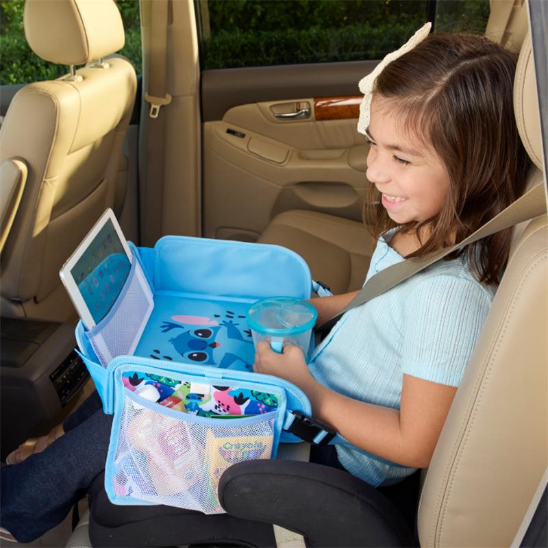 Toddler girl smiles while seated in a car, using a blue travel tray with a Stitch design for a tablet and drinks.