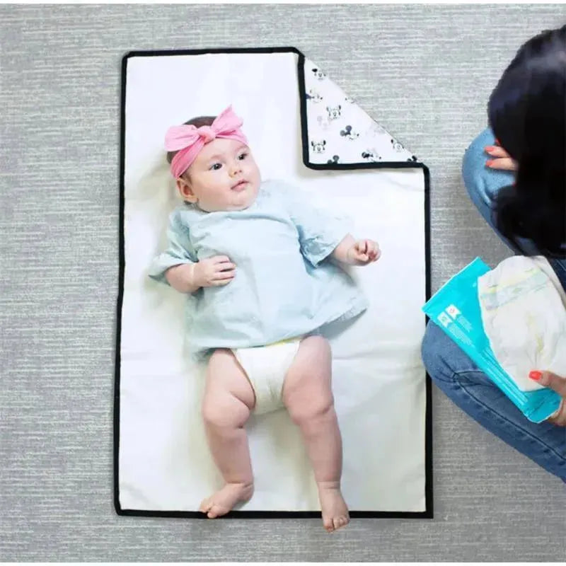 Disney Baby Full Body Changing Pad featuring Minnie Mouse print, with a baby in a diaper and a caregiver preparing diapers.