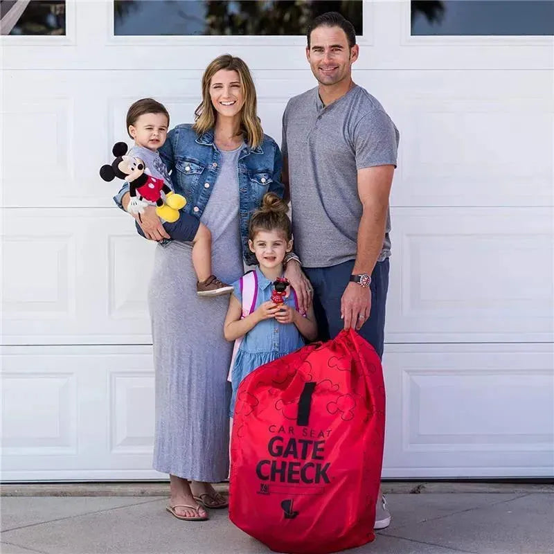 Family standing outside with a J.L. Childress Gate Check Bag for car seats in red, featuring a Mickey Mouse design.