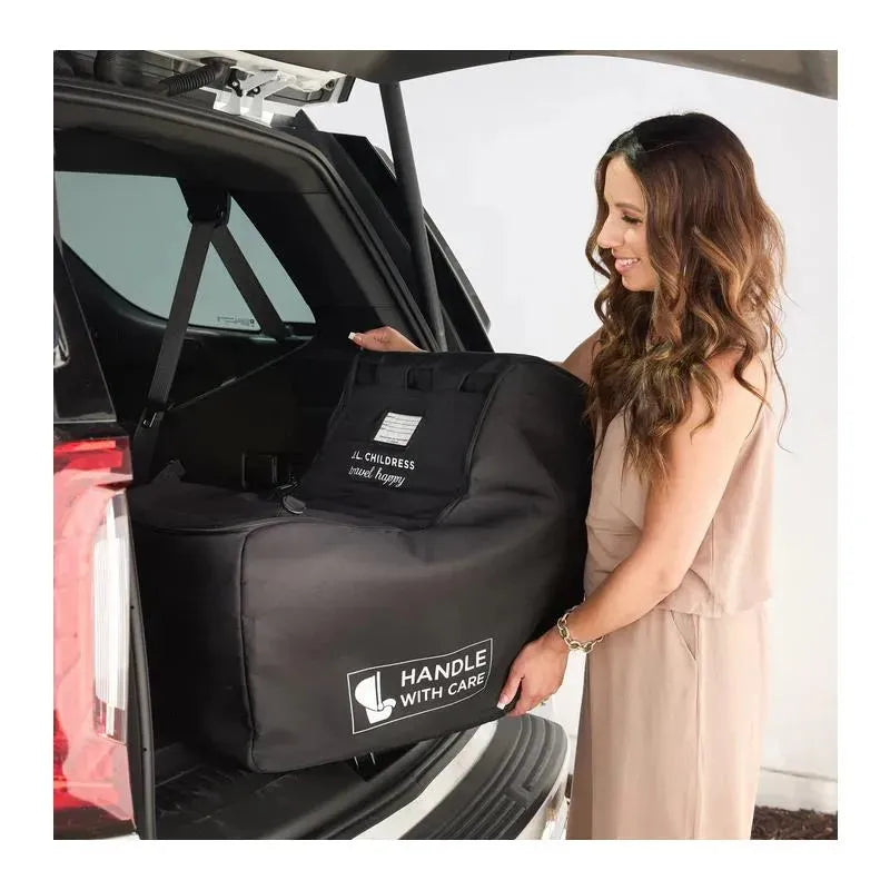 J.L. Childress padded infant car seat travel bag in black, with a woman handling it in the trunk of an SUV.