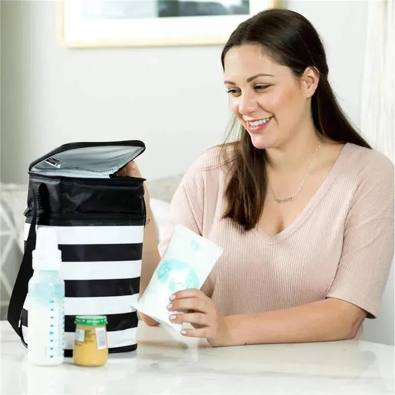 A woman holds a J.L. Childress reusable ice pack near a striped cooler bag, alongside a baby bottle and jar of food.