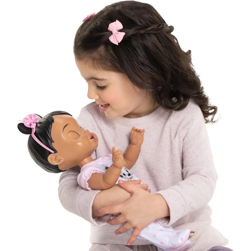 A smiling child with brown hair holds a 13-inch interactive baby doll with brown hair, wearing a cute outfit.